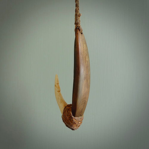 This picture shows a small sculptural hook called a pā kahawai. It is carved from whale bone, paua shell and wood, and is a colourful blue grey colour. It is shown on a stand made from argillite stone and is held in a brass cradle. One only, free shipping worldwide.