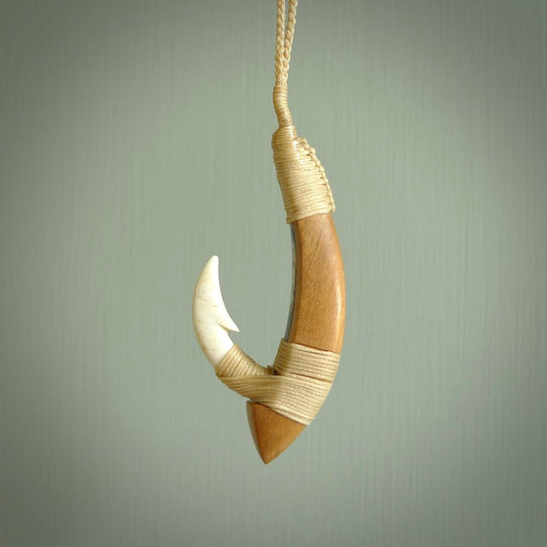 This picture shows a large matau, hook called a pā kahawai. It is carved from bone,  wood, and paua shell. One only, free shipping worldwide. Provided with an adjustable beige cord. Stunning work of Art to Wear by Andrew Doughty.