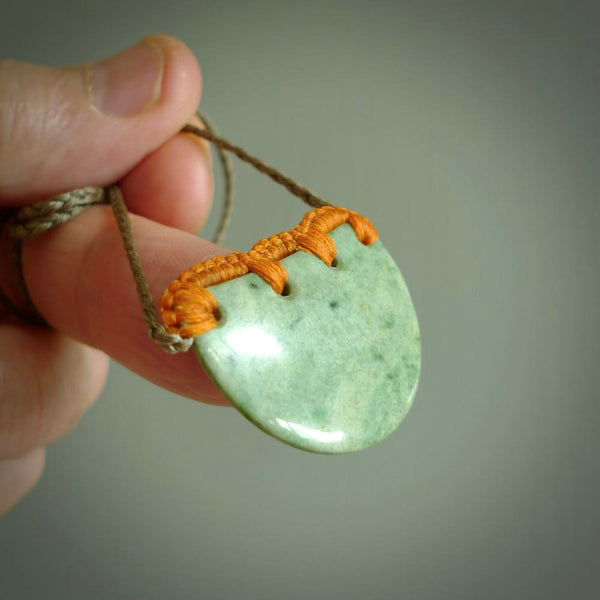 Hand carved Waimea pounamu disc pendant. These beautiful pieces have been carved for us by Raegan Bregmen and are quite beautiful. The soft green colours are lovely and are set off with a Khaki cord and Sunrise ridge binding.