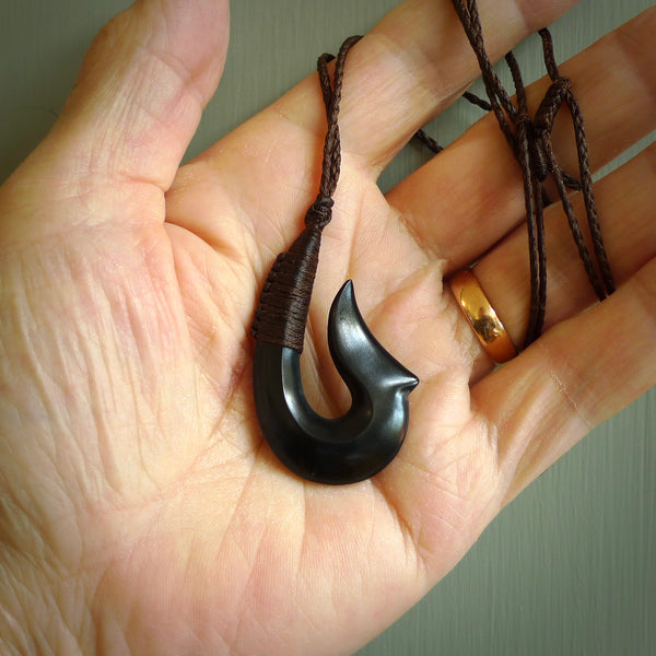 This piece is a hand carved black jade matau pendant, otherwise known as a traditional fish hook necklace. This piece has been carved by us and is made from a wonderful lustrous black jade that we source in Australia. It is a striking traditional piece which we hand bind with a Brown/Flax coloured cord. Delivery is free worldwide.