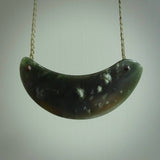 This picture shows a hand carved jade contemporary half-shield pendant. It is a deep green colour and is a wonderful, delicate piece of jewellery. The cord is hand plaited and adjustable so that you can position the pendant where it suits you best. This piece was carved for us by Darren Hill. Delivery is free worldwide.