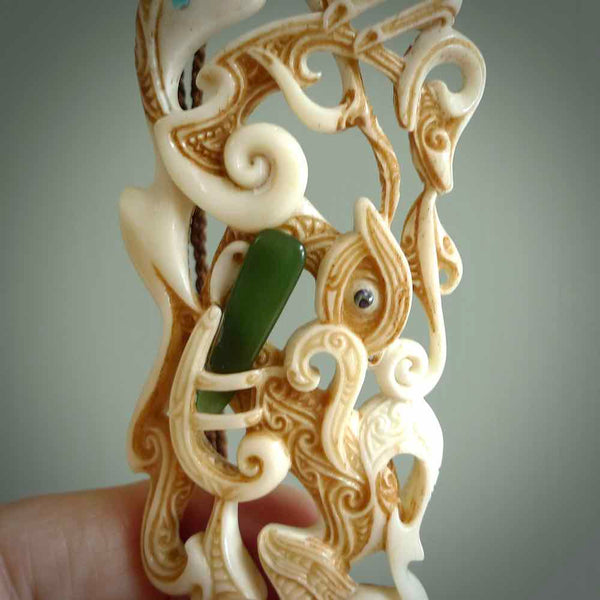 Hand carved bone manaia pendant. This is a complex carving by New Zealand carver and artist, Andrew Doughty. It is an intricate representation of a manaia carved to represent protection. It can be worn but is also a quality that warrants display.