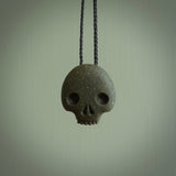 Greywacke Beach Stone skull pendant hand made here in New Zealand. Hand carved by Rhys Hall for NZ Pacific. Handmade jewellery for sale online. The cord is black and has a loop and pebble toggle closure. Unique necklace for men and women. Skull necklace hand made from New Zealand Greywacke Beach Stone.