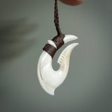 Hand carved cow bone hook pendant. Maori matau carving, hand carved jewellery for sale online.