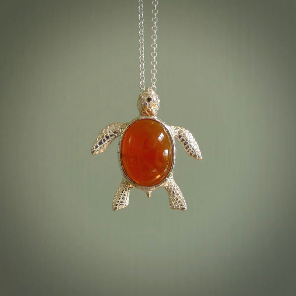 Fire Agate stone turtle in Sterling silver engraved casing. Hand carved jewellery made by NZ Pacific and for sale online. Moana, Ocean, jewellery hand carved in fire agate and Sterling Silver turtle necklace.