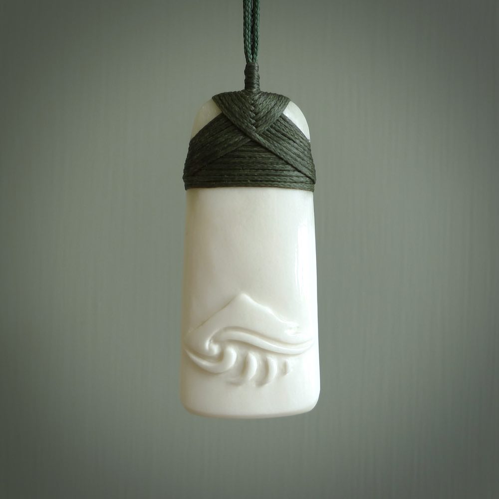A hand carved bone toki with NZ Pacific logo engraving. Unique hand made jewellery from New Zealand Pacific.
