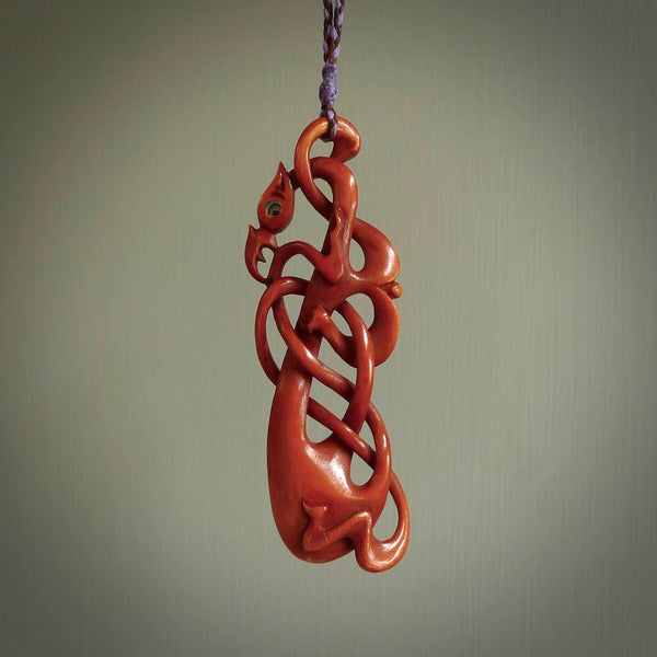 A one off beautiful piece of carved art. Hand carved for us by Yuri Terenyi and is an intricate and complex twist with manaia pendant. This is a wonderful ethnic bone pendant designed to be worn. It has been stained by a homemade tea dye in a bright gingery brown colour and we have hand plaited an adjustable cord in brown and lilac with a lilac floret popper.