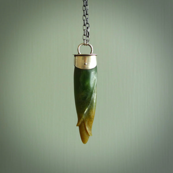 This picture shows a hand carved flower jade drop pendant with sterling silver cap and chain. The jade is a very dark green with a shimmer of orange tones in the stone. It is suspended from a sterling silver clasp and we supply a sterling silver chain. Delivery is free worldwide.