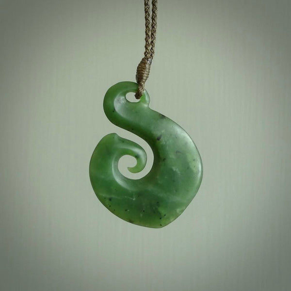 This matau, with koru, is carved from a very striking New Zealand jade. It is both intricate and simple in design - it has hidden folds and smooth curves. A piece to be worn or displayed - the carving and the jade are both magnificent.