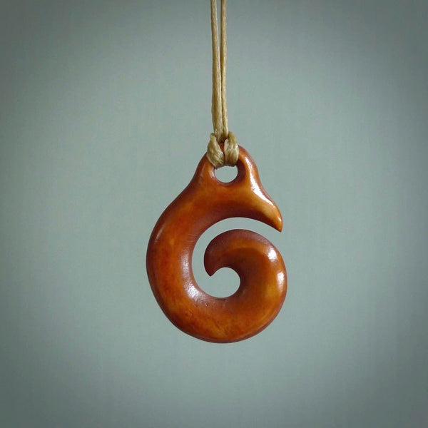 Stained natural cow bone hook with koru pendant. Hand carved by Yuri Terenyi in New Zealand. Maori design pendant for sale online. One only natural bone hook with koru necklace. Free delivery worldwide.