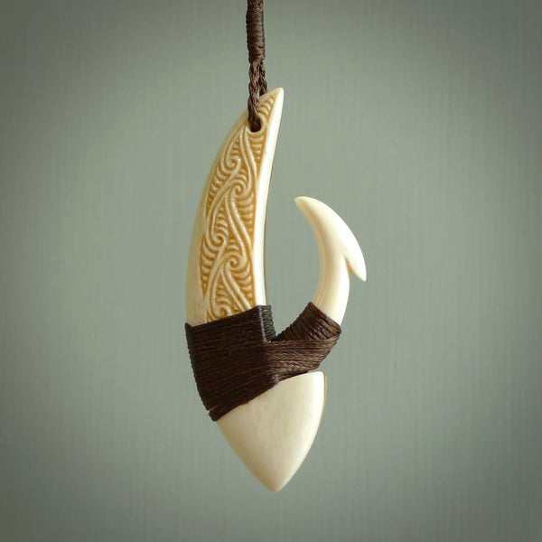 This picture shows a large matau, hook called a pā kahawai. It is carved from bone,  wood, and copper. One only, free shipping worldwide. Provided with an adjustable brown cord. Stunning work of Art to Wear by Andrew Doughty.