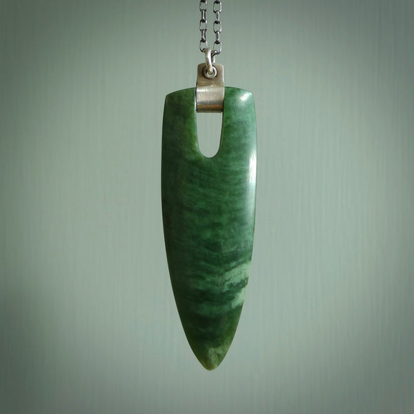 This is a chatoyant green contemporary Drop, tooth style pendant carved here in New Zealand by Josey Coyle. It is carved from a piece of rare New Zealand Inanga Pounamu, Jade with Sterling Silver. The jade is a subtle deep green colour. A very finely carved pendant with a sterling silver chain necklace.