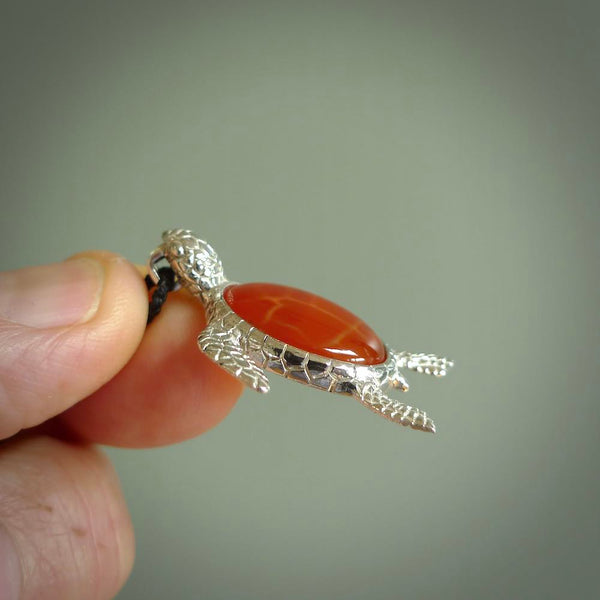 Fire Agate stone turtle in Sterling silver engraved casing. Hand carved jewellery made by NZ Pacific and for sale online. Moana, Ocean, jewellery hand carved in fire agate and Sterling Silver turtle necklace.