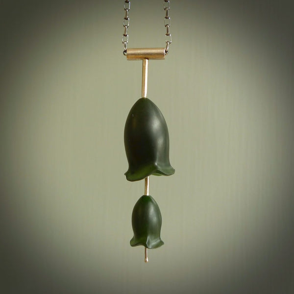 This is a very dark green flower bud pendant carved here in New Zealand by Josey Coyle. It is handmade carved jade double flower buds one placed above the other on a fine silver wire. The top is a T-shaped tube through which a silver necklace chain passes. The jade florets are handcarved from beautiful dark green New Zealand Marsden Jade and the chain is handmade from sterling silver wire.