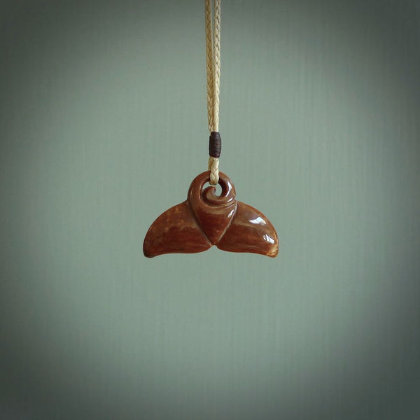 This photo shows a small whaletail pendant that we have carved from a dark honey coloured piece of Woolly Mammoth tusk. It is suspended on a Pale straw coloured cord that is length adjustable.