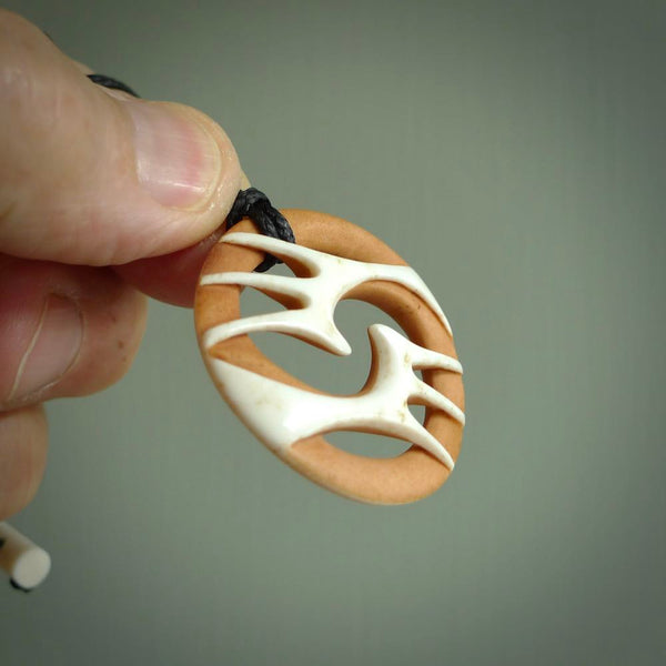 A hand carved bone contemporary, intricate pendant. The cord is a black colour and is a fixed length. A medium sized hand made contemporary necklace by New Zealand artist Kerry Thompson. Kerry has stained parts of the bone which really add to the dimension of this pendant. One off work of art to wear.