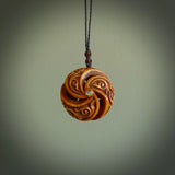 A hand carved and intricate koru pendant made for us by Yuri Terenyi. This is a beautiful little piece and is emblematic of the well known and loved Koru design. It is carved from bone in a hollowed, oval ball shape with decorative design carved into the koru. It is suspended from a Black cord with a wapiti brown floret and the necklace is adjustable.
