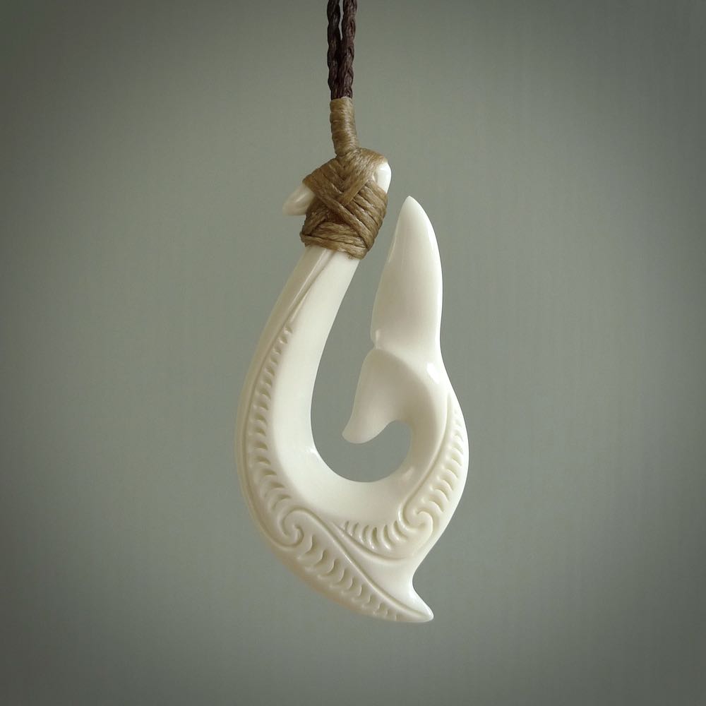 A handcarved hook pendant with a whaletail end. This is carved from bone and is detailed with a traditional Maori engraved design. We will ship this piece to you anywhere in the world and the price for shipping is included in the price. Unique bone jewellery for sale online at www.nzpacific.com