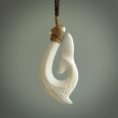 A handcarved hook pendant with a whaletail end. This is carved from bone and is detailed with a traditional Maori engraved design. We will ship this piece to you anywhere in the world and the price for shipping is included in the price. Unique bone jewellery for sale online at www.nzpacific.com