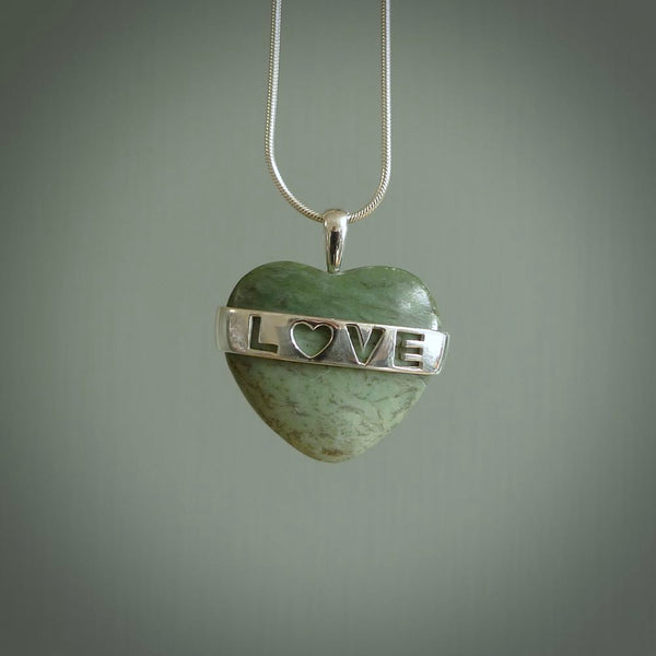 Hand crafted New Zealand jade love heart necklace. This piece has  a sterling silver love written across its' body. This necklace is provided with a sterling silver chain.