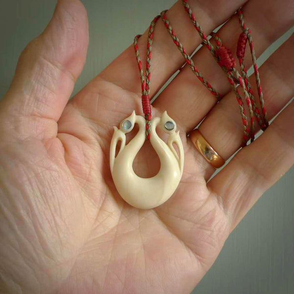 This is a unique double manaia, pekapeka, handcarved bone pendant from cow bone. The cord is Red and Khaki and is length adjustable. This is delivered to you with Express Courier. The eyes are made from Paua shell.