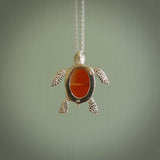 Fire Agate stone turtle in Sterling silver engraved casing. Hand carved jewellery made by NZ Pacific and for sale online. Moana, Ocean, jewellery hand carved in fire agate and Sterling Silver turtle necklace.