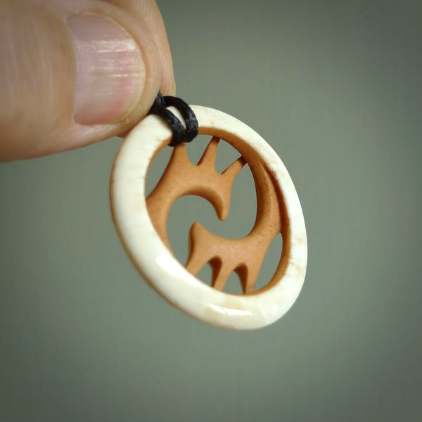 A hand carved bone contemporary, intricate pendant. The cord is a black colour and is a fixed length. A medium sized hand made contemporary necklace by New Zealand artist Kerry Thompson. Kerry has stained parts of the bone which really add to the dimension of this pendant. One off work of art to wear.