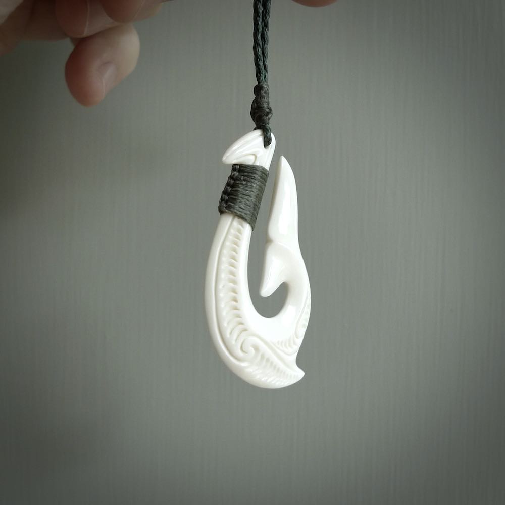 A handcarved hook pendant with a whaletail end. This is carved from bone and is detailed with a traditional Maori engraved design. We will ship this piece to you anywhere in the world and the price for shipping is included in the price. Unique bone jewellery for sale online at www.nzpacific.com