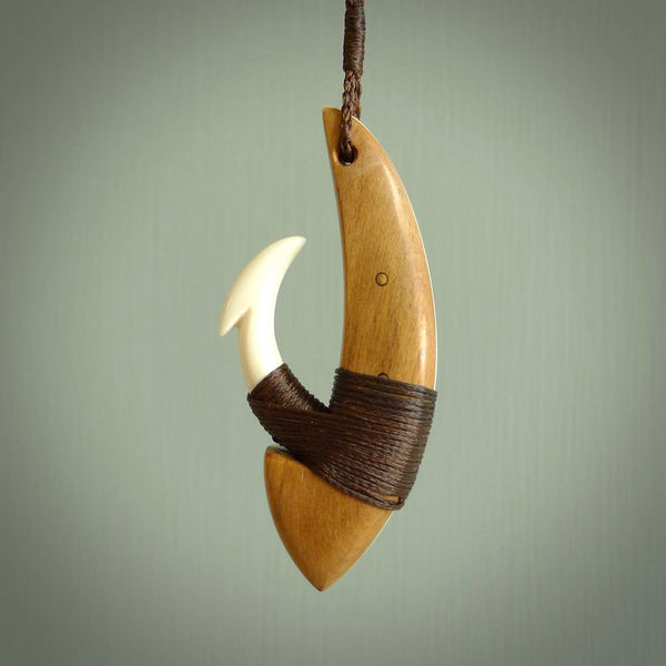 This picture shows a large matau, hook called a pā kahawai. It is carved from bone,  wood, and copper. One only, free shipping worldwide. Provided with an adjustable brown cord. Stunning work of Art to Wear by Andrew Doughty.