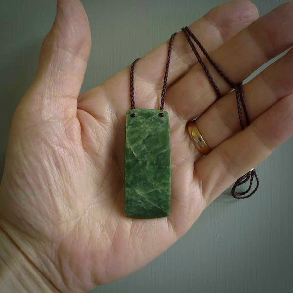 New Zealand Jade, Pounamu Toki pendant. Hand carved by Darren Hill for NZ Pacific. Handmade jewellery for sale online. The cord is plaited in brown and is adjustable. Toki necklace for men and women. Contemporary Toki necklace hand made from New Zealand Jade.