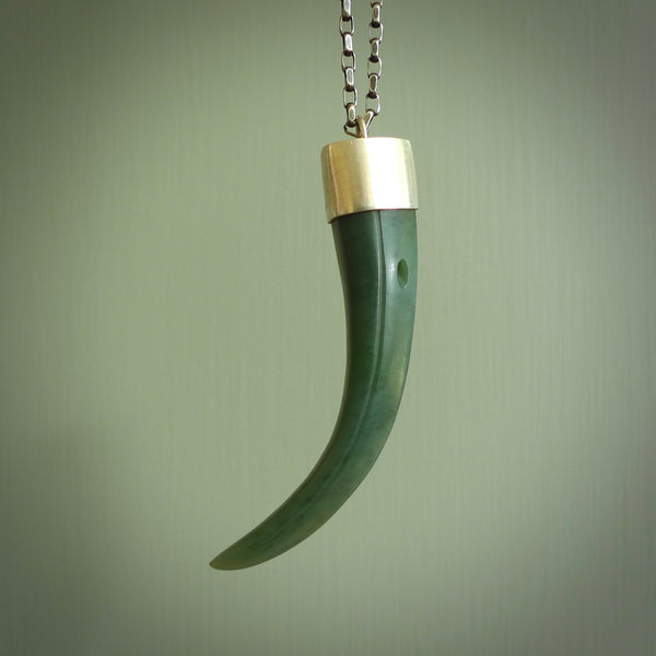 This picture shows a hand carved Inanga jade huia beak pendant with sterling silver cap and chain. The jade is a very dark green. It is suspended from a sterling silver clasp and we supply a sterling silver chain. Delivery is free worldwide.