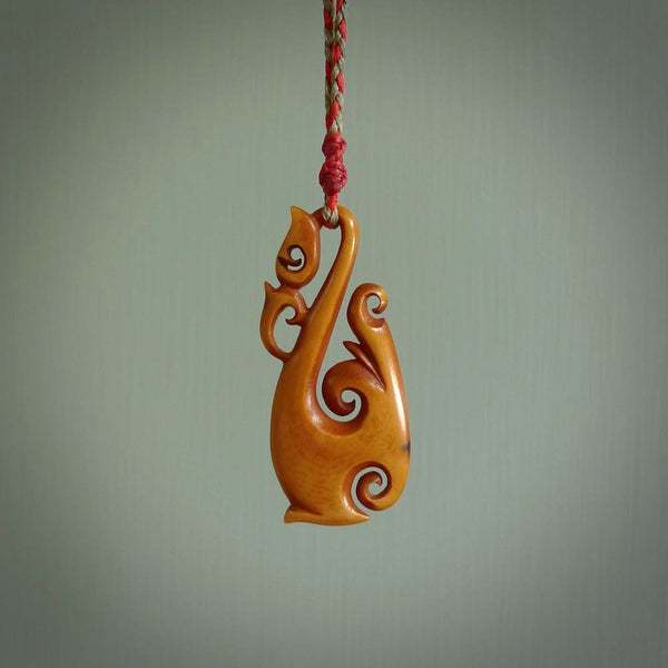 Natural stained cow bone manaia, hook with koru pendant. Hand carved by Yuri Terenyi in New Zealand. Maori design pendant for sale online. One only stained bone manaia, hook with koru necklace. Free delivery worldwide.