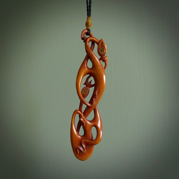 A one off beautiful piece of carved art. Hand carved for us by Yuri Terenyi and is a double manaia pendant. This is a wonderful ethnic bone pendant designed to be worn. It has been stained by a homemade tea dye in a bright gingery brown colour and we have hand plaited an adjustable cord in black with a burnt gold floret popper.