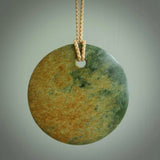 This piece is a large oval round, disc pendant. It was carved for us by Ric Moor from a lovely orange and green piece of New Zealand flower jade. It is suspended on a beige coloured braided cord that is length adjustable.