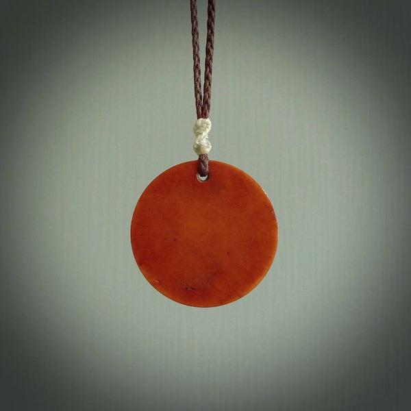 Hand carved natural stained bone contemporary disc pendant with creative and unique carvings on the front face of each individual piece.