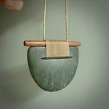 Raukaraka Pounamu breastplate pendant with rata wood. Hand carved by Rhys Hall for NZ Pacific. Handmade jewellery for sale online. The cord is a 3-braid plait in beige and has a loop and pebble toggle closure. Breastplate necklace for men and women. Scandinesian breastplate necklace hand made from New Zealand Jade.