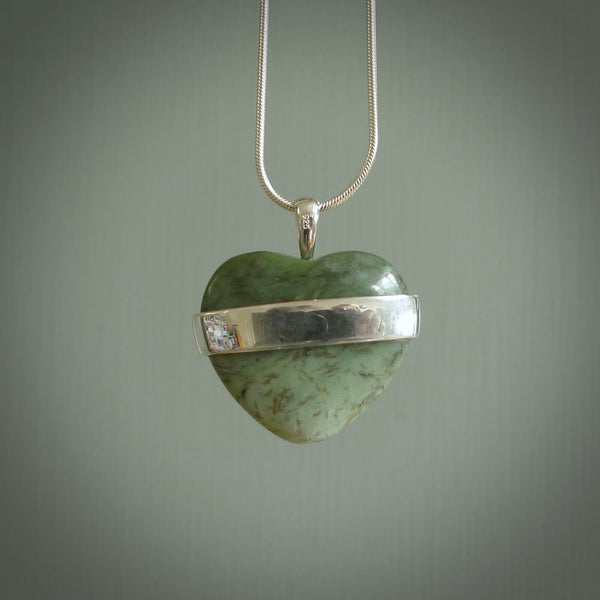 Hand crafted New Zealand jade love heart necklace. This piece has  a sterling silver love written across its' body. This necklace is provided with a sterling silver chain.