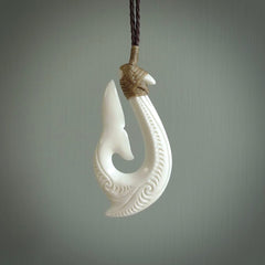 A handcarved hook pendant with a whaletail end. This is carved from bone and is detailed with a traditional Maori engraved design. We will ship this piece to you anywhere in the world and the price for shipping is included in the price. Unique bone jewellery for sale online at www.nzpacific.com
