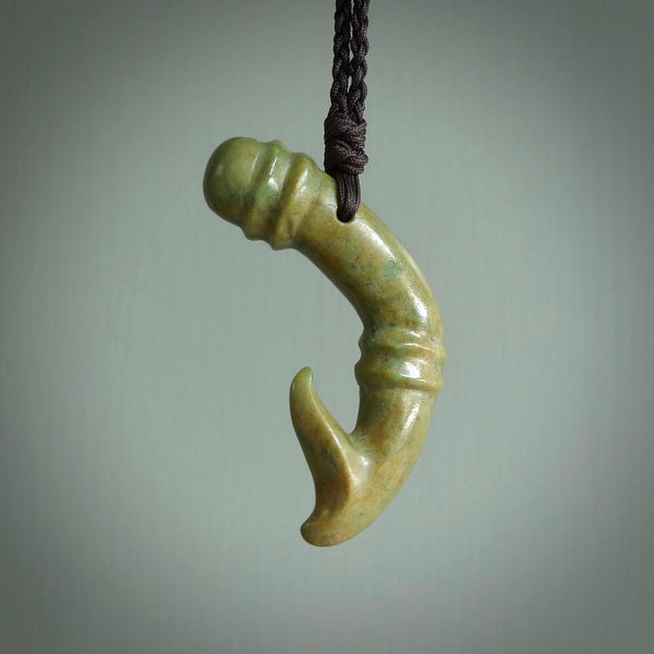 This photo shows a beautiful flower jade bamboo hook suspended from a hand plaited brown cord. The bamboo hook was carved for us by Jen Hung who is a master jade carver from New Zealand.