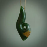 A hand carved hei-matau with koru pendant. This pendant is a green and orange colour and is finished in a polished matte. The cord is a four plait in beige and it is adjustable. Hand carved large Hook with Koru pendant by Ric Moor. Delivered to you with DHL Express Courier at no extra cost. One only necklace.