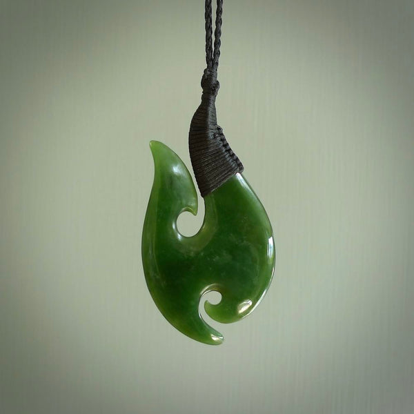 This is a beautiful New Zealand Pounamu, jade hook with a little decorative koru carved into the bottom. It is a chunky piece but beautifully balanced so doesn't look heavy. The cord is a Black colour and the binding on the top is also black.