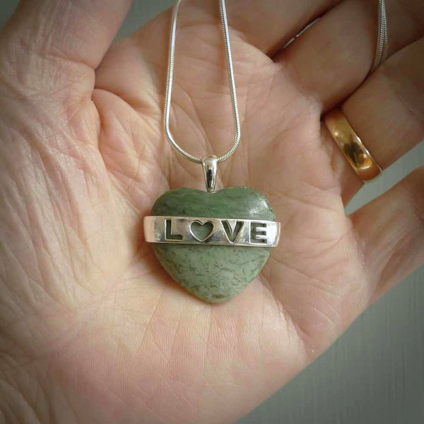 Hand crafted New Zealand jade love heart necklace. This piece has  a sterling silver love written across its' body. This necklace is provided with a sterling silver chain.