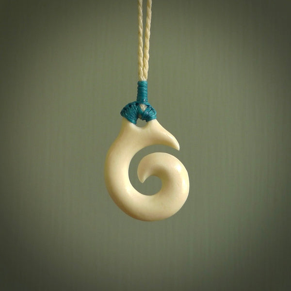 Natural cow bone hook with koru pendant. Hand carved by Yuri Terenyi in New Zealand. Maori design pendant for sale online. One only natural bone hook with koru necklace. Free delivery worldwide.