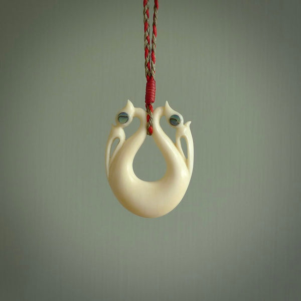 This is a unique double manaia, pekapeka, handcarved bone pendant from cow bone. The cord is Red and Khaki and is length adjustable. This is delivered to you with Express Courier. The eyes are made from Paua shell.