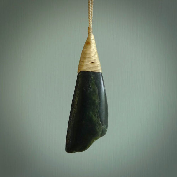 This photo shows a large jade drop shaped pendant. It a a lovely deep green jade. The cord is a four plait beige and is adjustable in length. One only large, contemporary drop necklace from Jade, by Ric Moor.