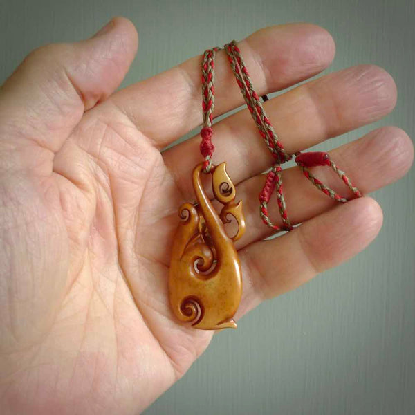 Natural stained cow bone manaia, hook with koru pendant. Hand carved by Yuri Terenyi in New Zealand. Maori design pendant for sale online. One only stained bone manaia, hook with koru necklace. Free delivery worldwide.