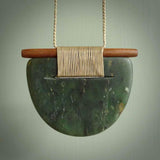 Raukaraka Pounamu breastplate pendant with rata wood. Hand carved by Rhys Hall for NZ Pacific. Handmade jewellery for sale online. The cord is a 3-braid plait in beige and has a loop and pebble toggle closure. Breastplate necklace for men and women. Scandinesian breastplate necklace hand made from New Zealand Jade.