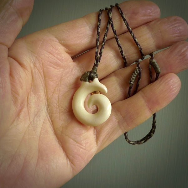 Natural cow bone hook with koru pendant. Hand carved by Yuri Terenyi in New Zealand. Maori design pendant for sale online. One only natural bone hook with koru necklace. Free delivery worldwide.