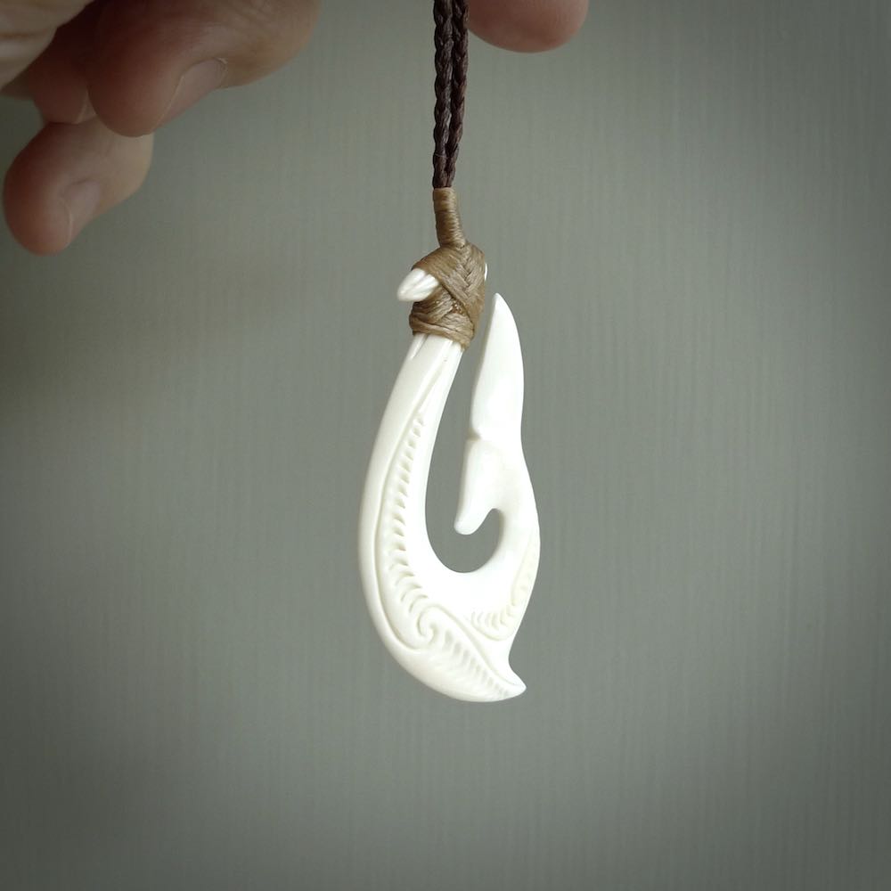A handcarved hook pendant with a whaletail end. This is carved from bone and is detailed with a traditional Maori engraved design. We will ship this piece to you anywhere in the world and the price for shipping is included in the price. Unique bone jewellery for sale online at www.nzpacific.com