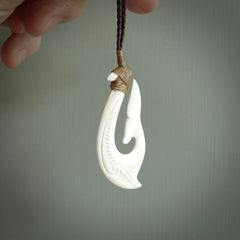 A handcarved hook pendant with a whaletail end. This is carved from bone and is detailed with a traditional Maori engraved design. We will ship this piece to you anywhere in the world and the price for shipping is included in the price. Unique bone jewellery for sale online at www.nzpacific.com
